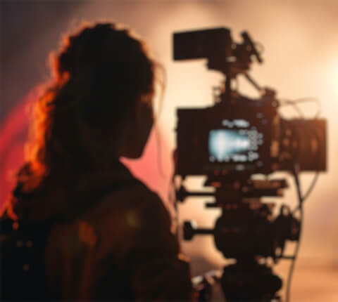 A woman standing in front of a movie camera on set