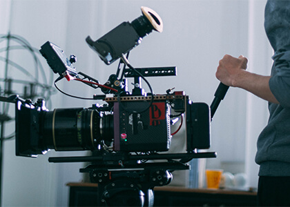 A man standing next to a movie camera on a tripod