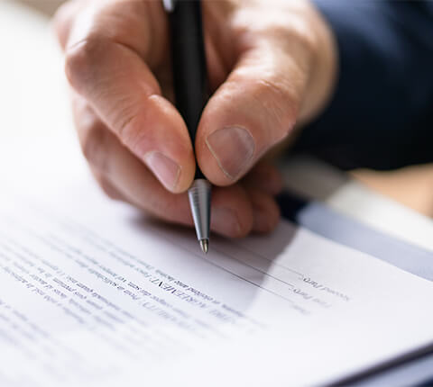 Close up of hand signing a document with pen