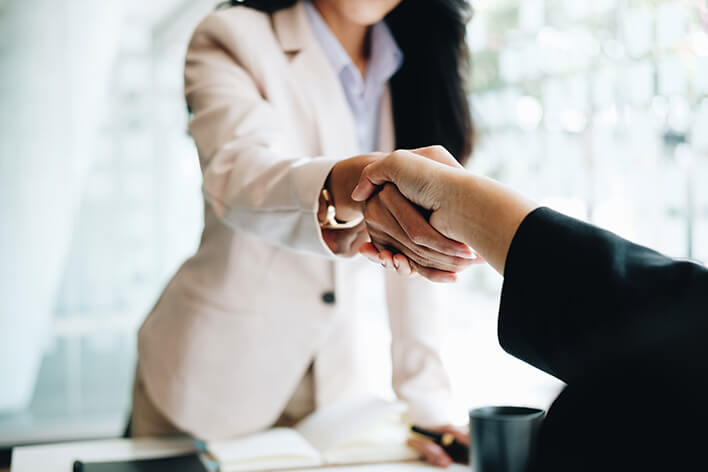 Woman shaking man's hand over a desk